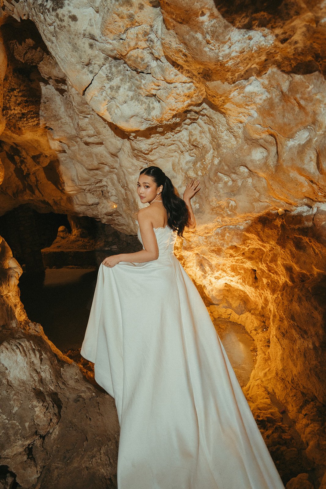 Bride Maria in a candlelit cave with her bouquet, bridal makeup by Tian Soon