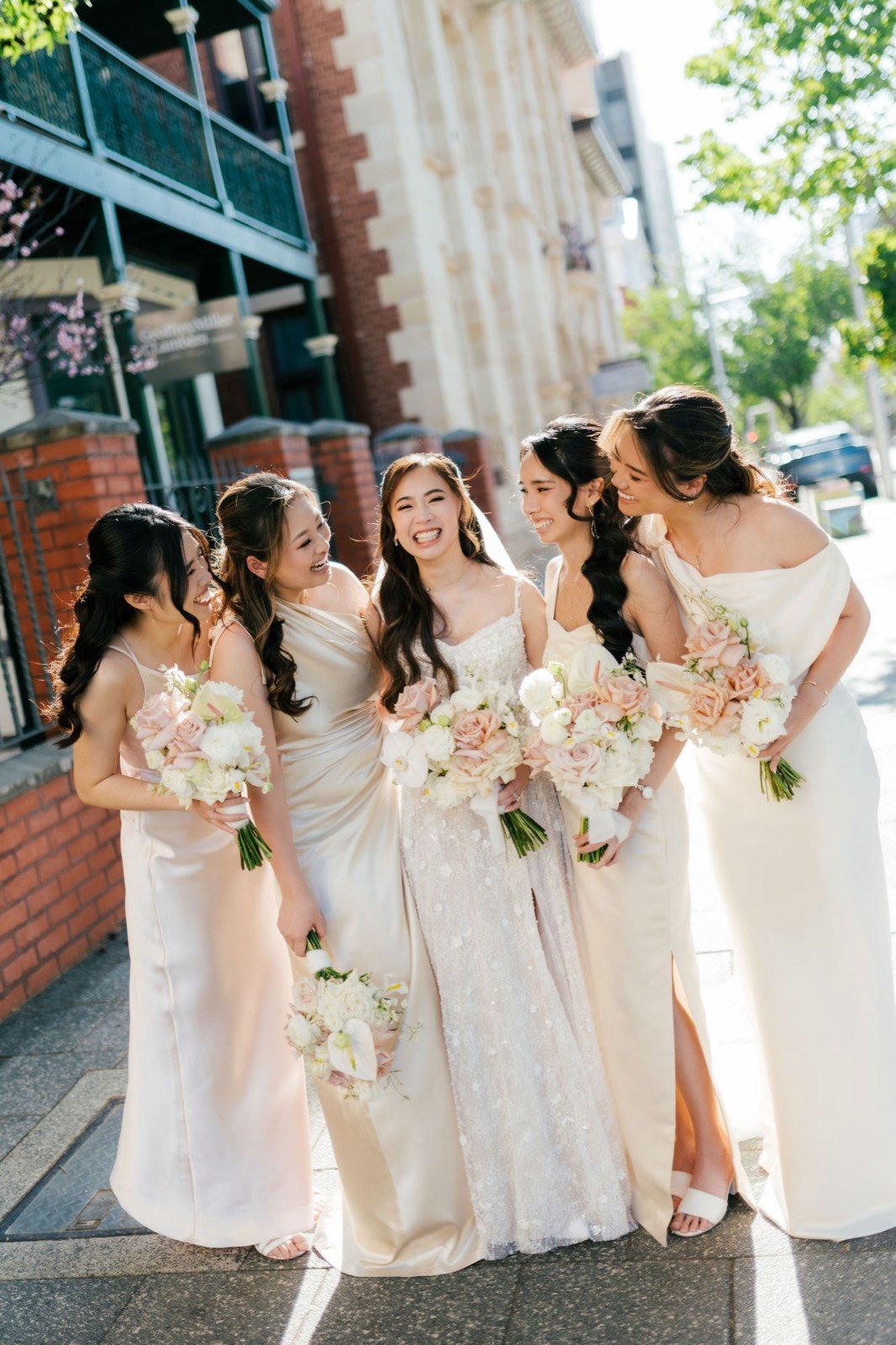 Bride Natalie laughing with her four bridesmaids in afternoon sunlight, bridal party makeup by Tian Soon
